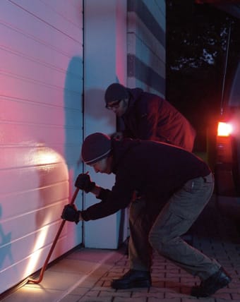 Dos ladrones intentan robar en un chalé a través de la puerta del garaje.