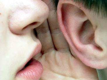 Dos personas cuchichean contándose secretos al oído.