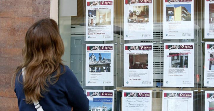 Mujer viendo ofertas en un escaparate de una inmobiliaria