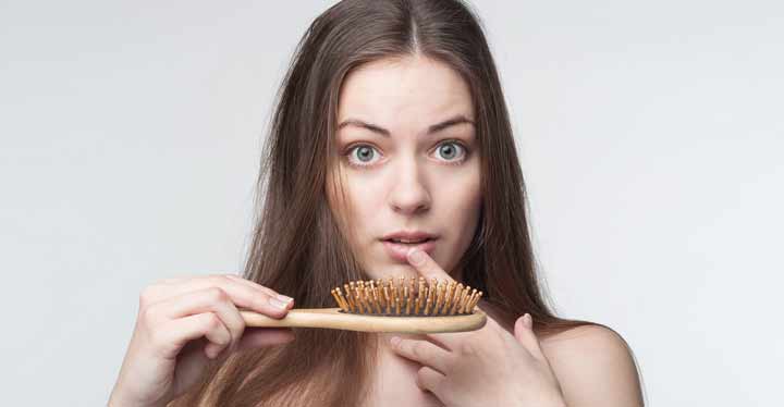 Mujer con cepillo del pelo que muestra la caída del cabello