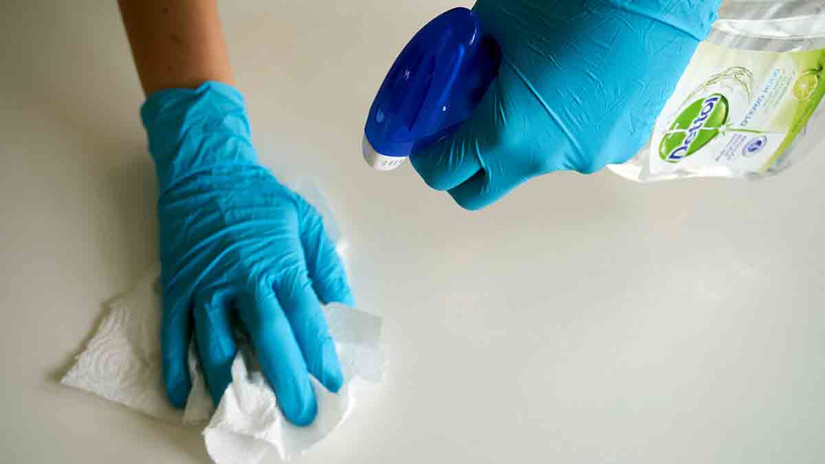Manos con guantes utilizando productos de limpieza