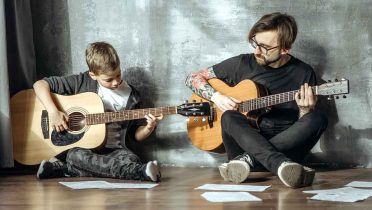 Profesor de guitarra enseñándole a un niño.