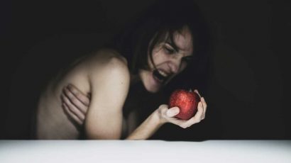 Mujer intentando morder una manzana.