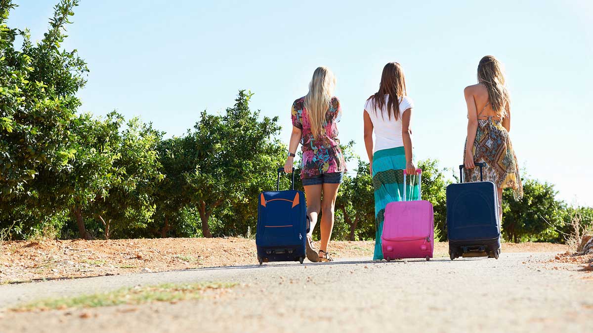 Chicas de vacaciones con una maleta.