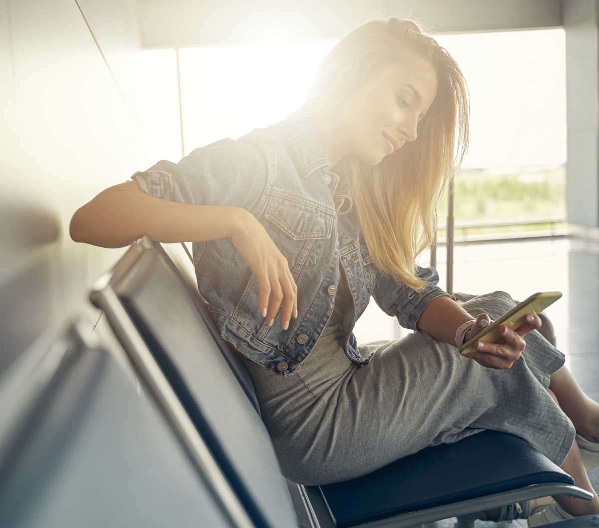 Mujer en el aeropuerto consultando el móvil.