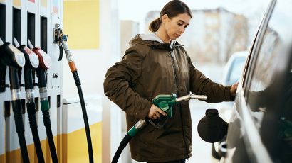 Una mujer reposta en una gasolinera con una tarjeta de descuento de un banco.