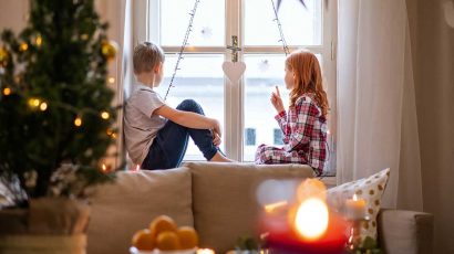 Dos niños en casa con decoración Navideña.