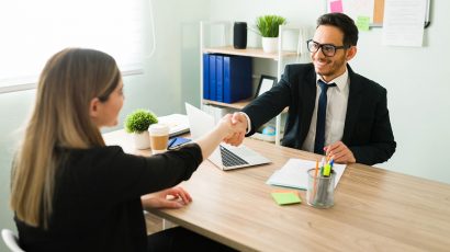 Una mujer estrechando la mano con su jefe de trabajo.