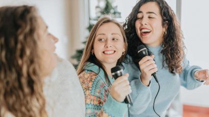Tres chicas con un micrófono cantando una canción.