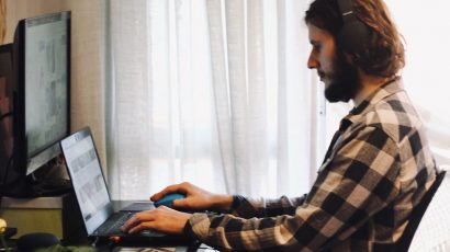 Hombre con unos auriculares teletrabajando desde casa.