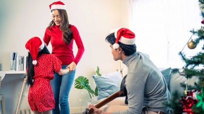Una familia con gorros de Navidad cantando villancicos.