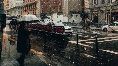 Una mujer paseando por Madrid con un paraguas mientras nieva.