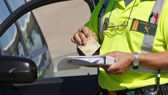 Un Guardia Civil de Tráfico cobrando una multa a un conductor.