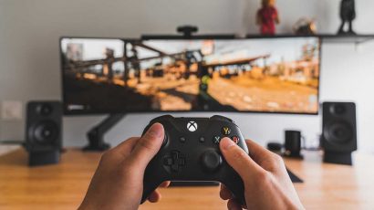 Una persona sujetando un mando de la XBOX mientras juega a un videojuego.