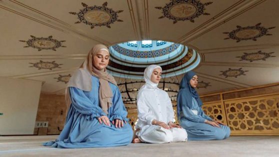 Tres mujeres rezando en una mezquita con ropa típica musulmana.