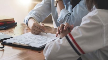 Dos personas negociando un contrato en una mesa.