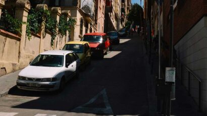 Coches aparcados en la calle al sol.