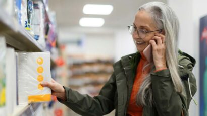 Una mujer compra en el supermercado mientras conversa por el móvil.