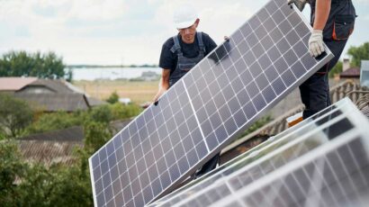 Unos profesionales instalando placas solares en un tejado.