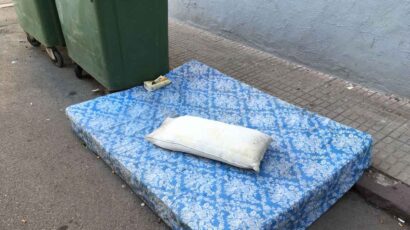 Un colchón tirado en la calle junto a los contenedores de basura.