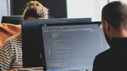 Unos empleados en su puesto de trabajo desarrollando código.