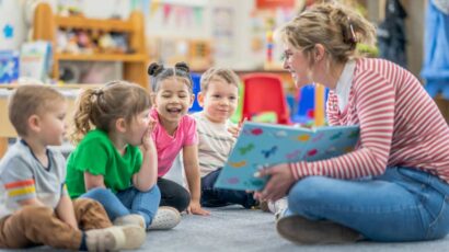 Una profesora de guardería lee un cuento a unos niños.