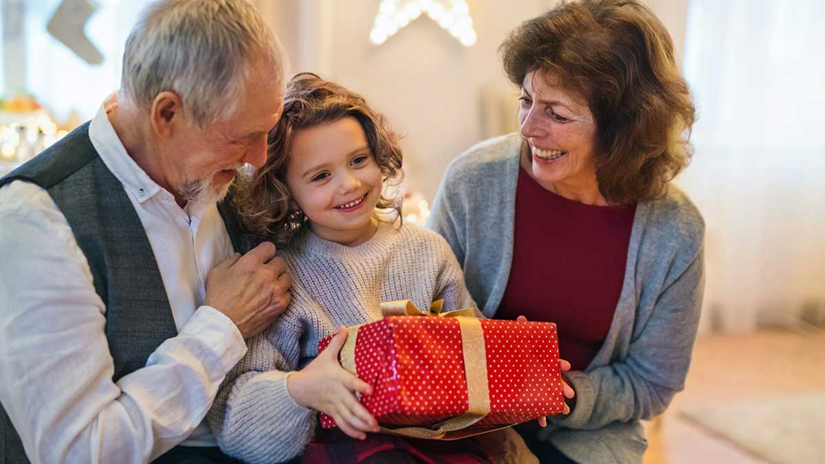 Unos jubilados entregan un regalo por Navidad a su nieta.