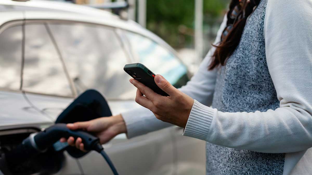 Una mujer coloca la manguera para recargar su vehículo eléctrico.