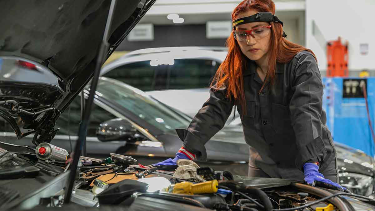 Una mecánica en medio de una reparación de un motor.