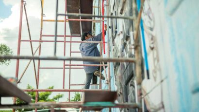 Un obrero subido a un andamio realiza trabajos de mejora de fachada.