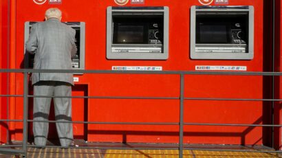 Un anciano saca dinero de un cajero automático de un banco.