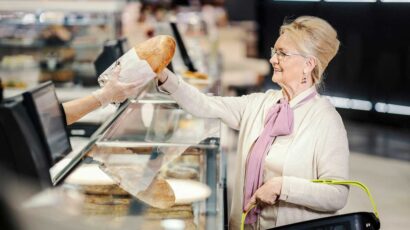 Una señora compra pan en una panadería.