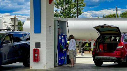 Una mujer carga combustible en su coche en garrafas.