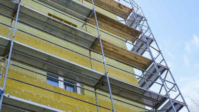 Un edificio rodeado por un andamio para la realización de mejoras de aislamiento y eficiencia energética.