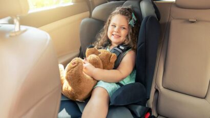 Una niña va al colegio en el coche de sus padres sentada perfectamente en la sillita de seguridad.